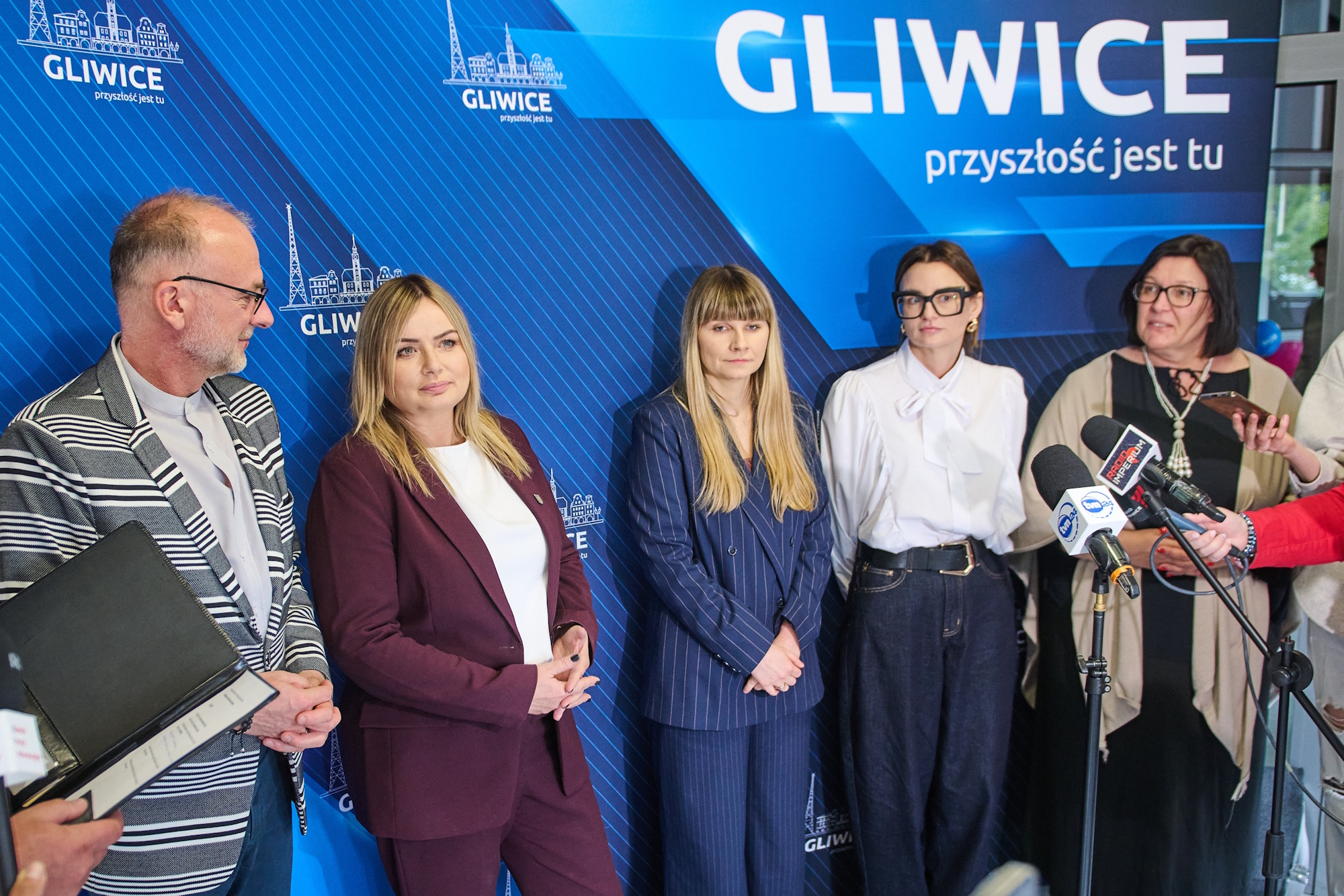 Konferencja prasowa podczas I Gliwickiego Forum Rodzicielstwa Zastępczego. Fot. M.Buksa/UM Gliwice osoby na ściance prasowej udzielają wywiadów podczas konferencji