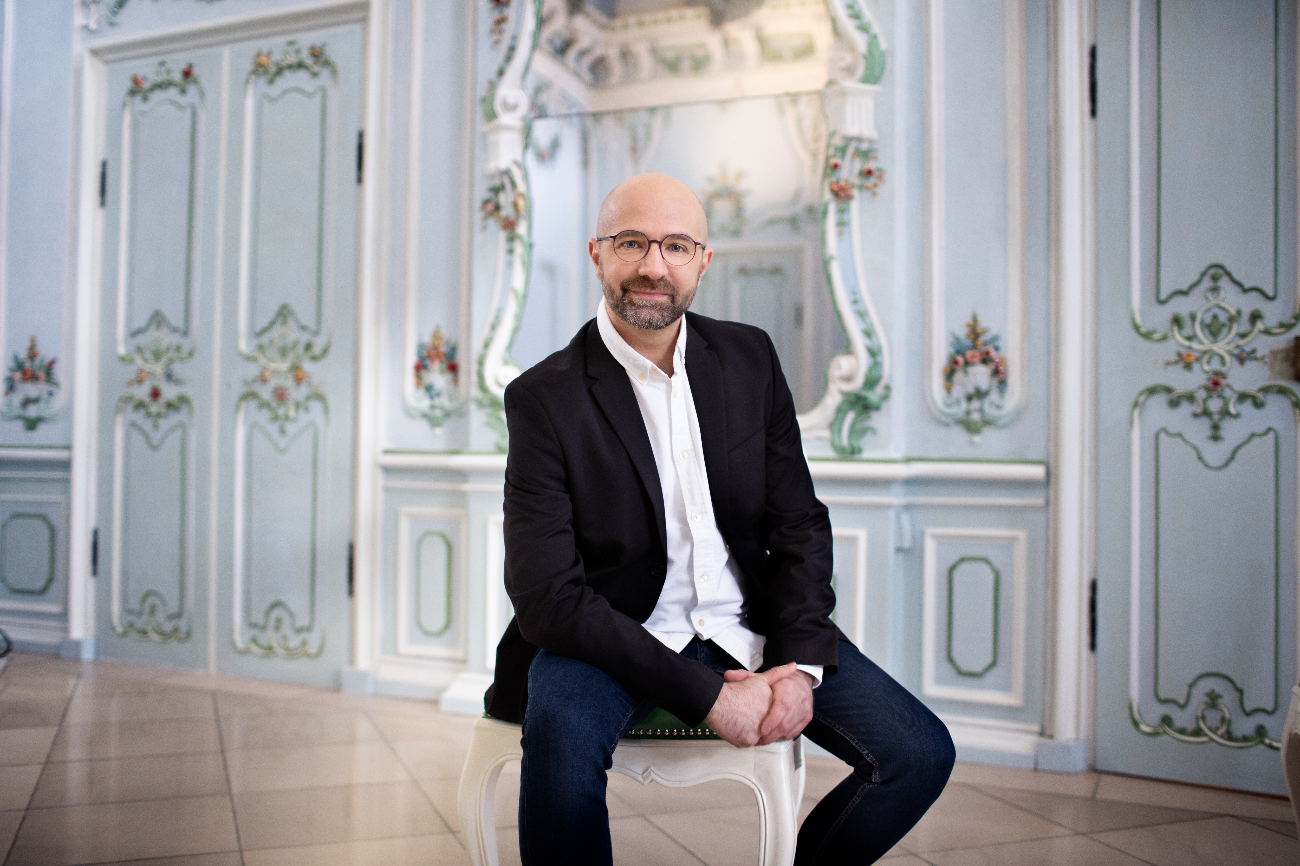 Max Emanuel Cenčić (fot. Ł. Rajchert) mężczyzna w garniturze siedzi na krześle