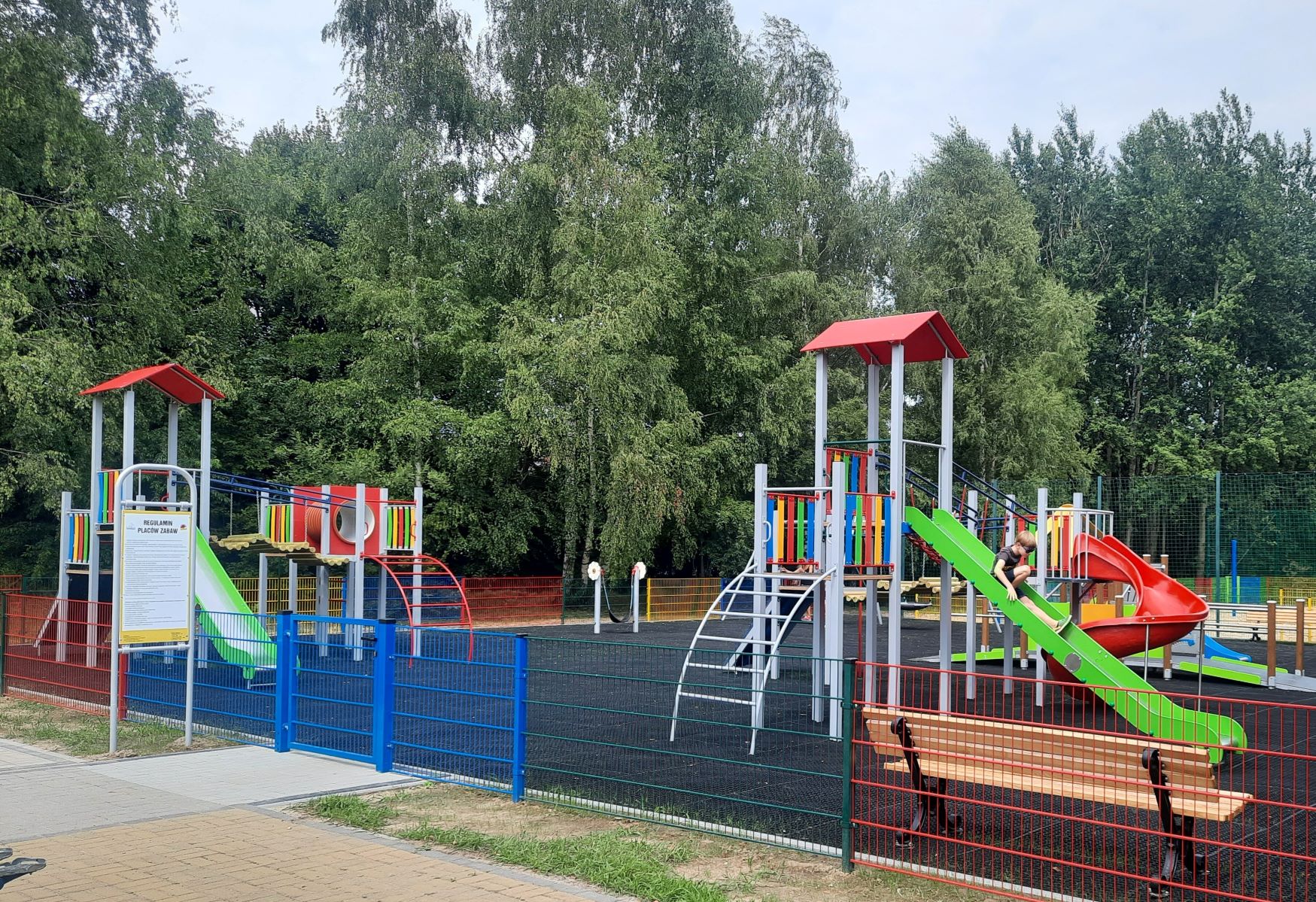 Plac zabaw w Żernikach (fot. materiały MZUK) widok na cały plac zabaw ze zjażdżalnią, ławką do siedzenia i innymi urządzeniami