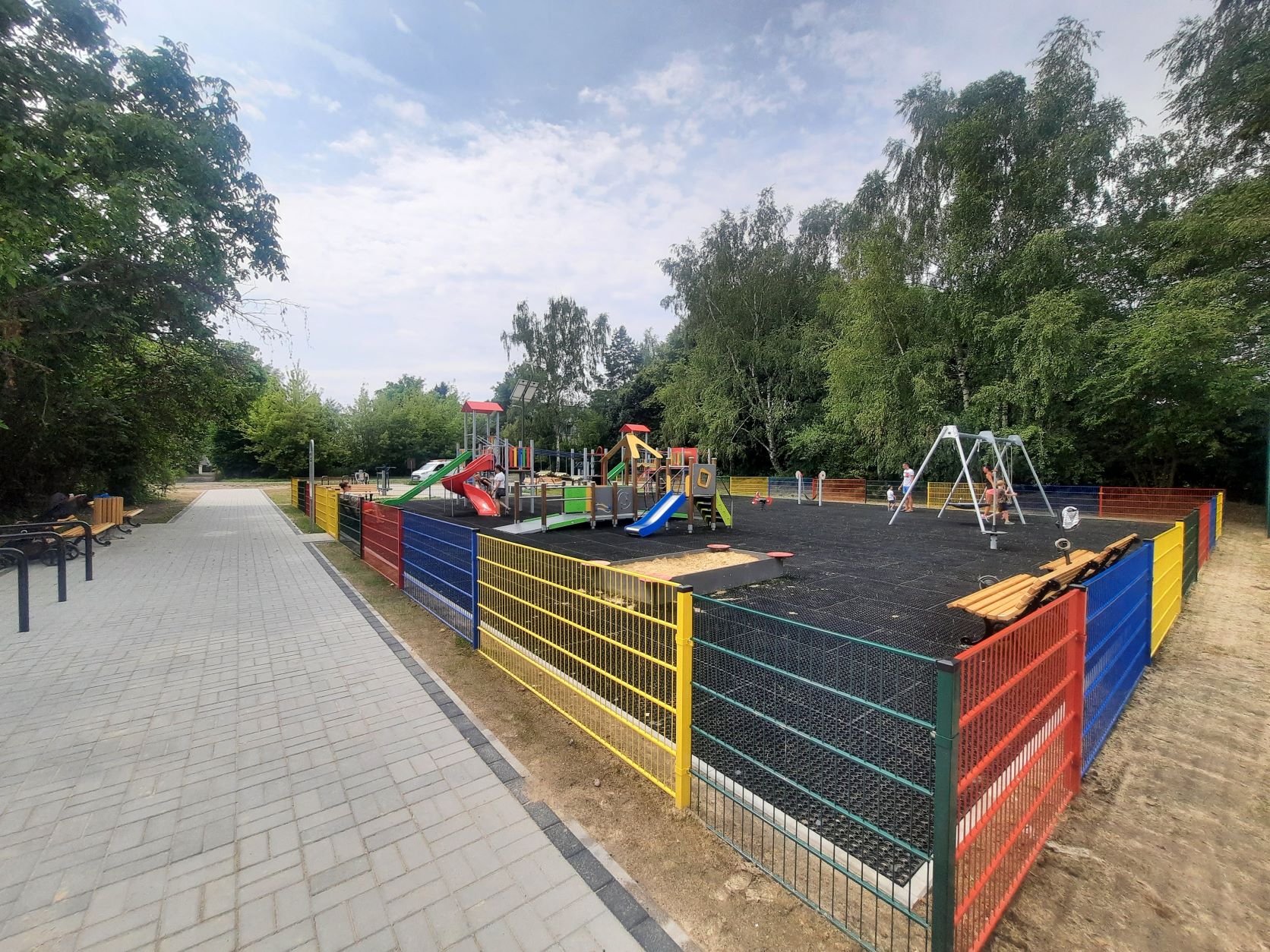 Plac zabaw w Żernikach (fot. materiały MZUK) widok na plac zabaw i kolorowe ogrodzenia, huśtawki