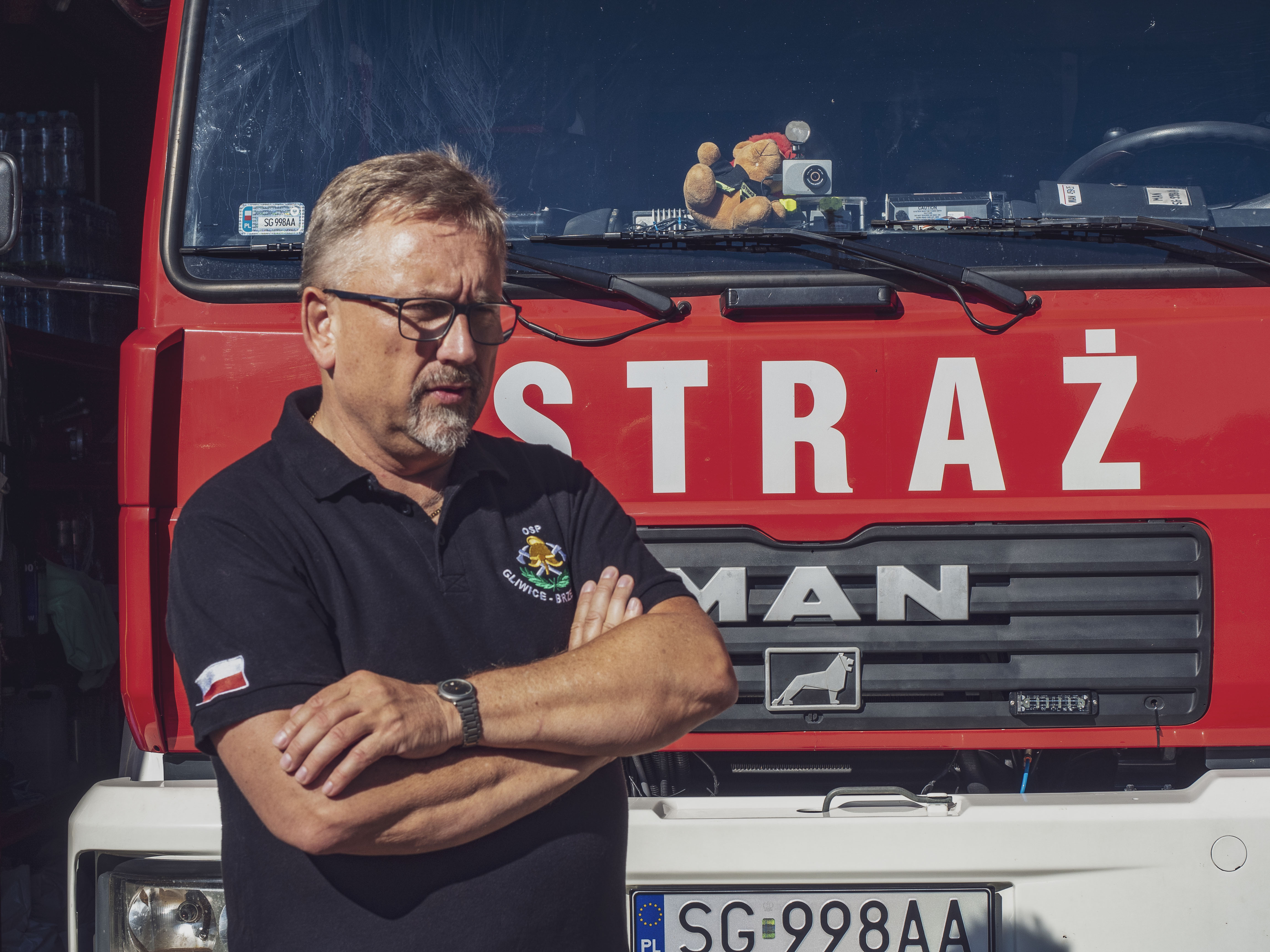 – Bycie ochotniczym strażakiem to pasja i wspaniała misja. Jedziemy na akcje nie dla honorów czy nagród. To, że możemy komuś pomóc i widzieć, jak wielkie miało to dla niego znaczenie, to najlepsza nagroda za każdą pomoc. Służba ludziom sprawia nam ogromną satysfakcję – mówi Tomasz Włoczyk, prezes OSP Brzezinka. Fot. G.Ożga/UM Gliwice strażak na tle samochodu