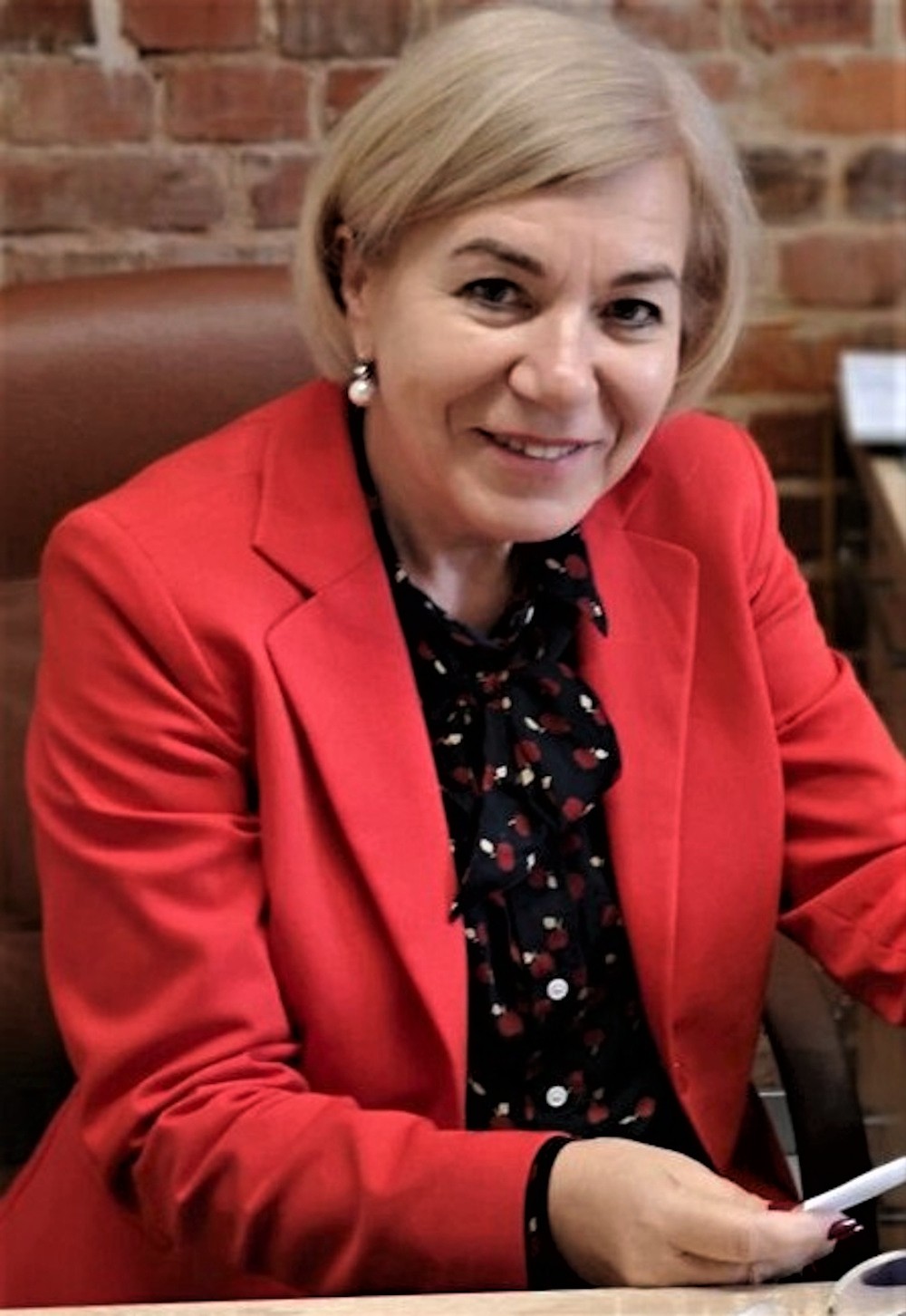 kobieta w czerwonym żakiecie siedzi przy biurku