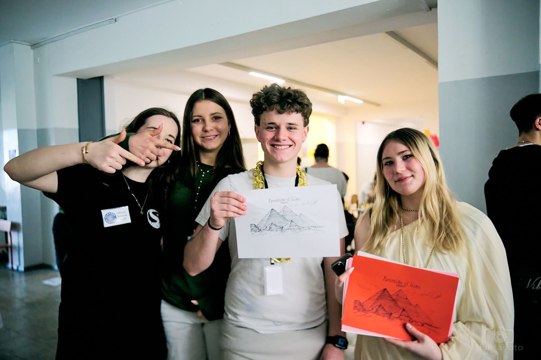 czworo młodych ludzi z rysunkami patrzy w obiektyw