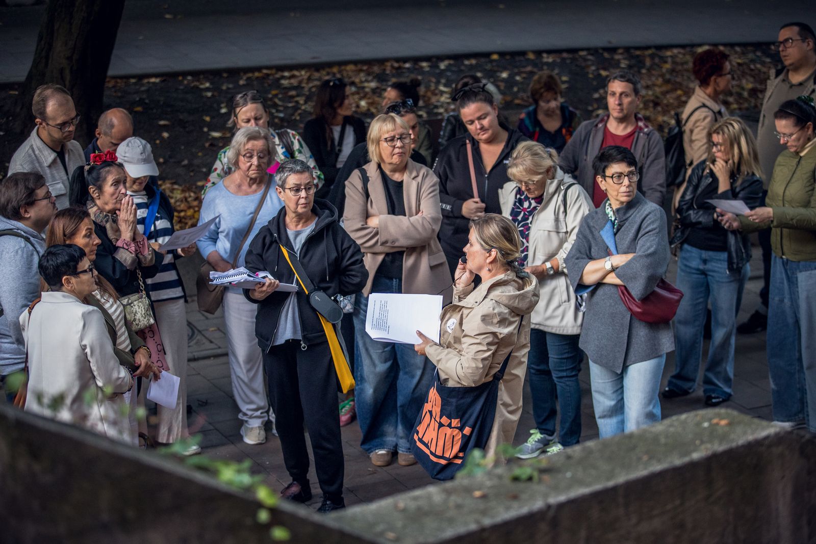Ludzie słuchający kobiety oprowadzającej trasą zabytków