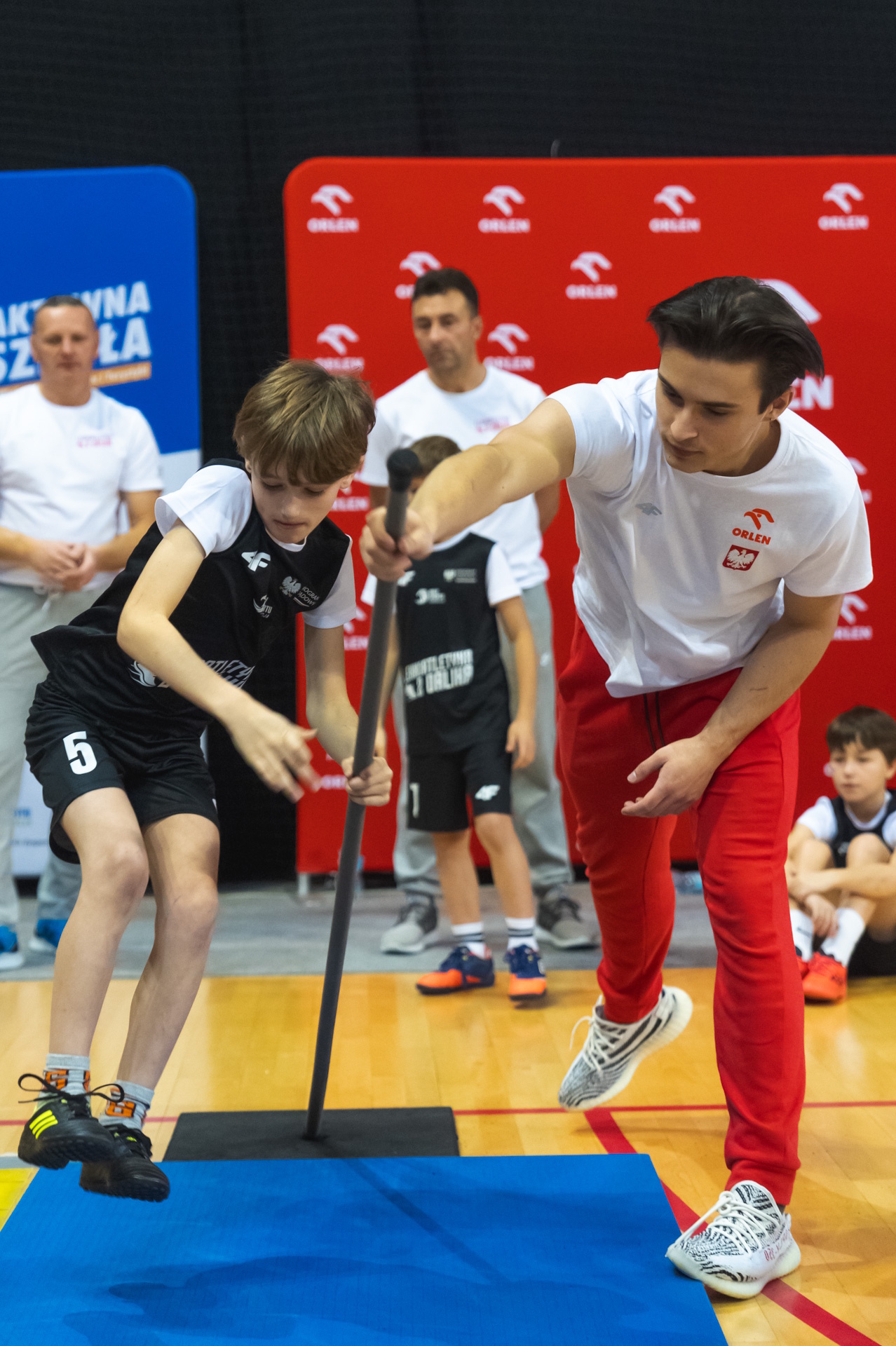 Chłopiec skaczący w dal o tyczce