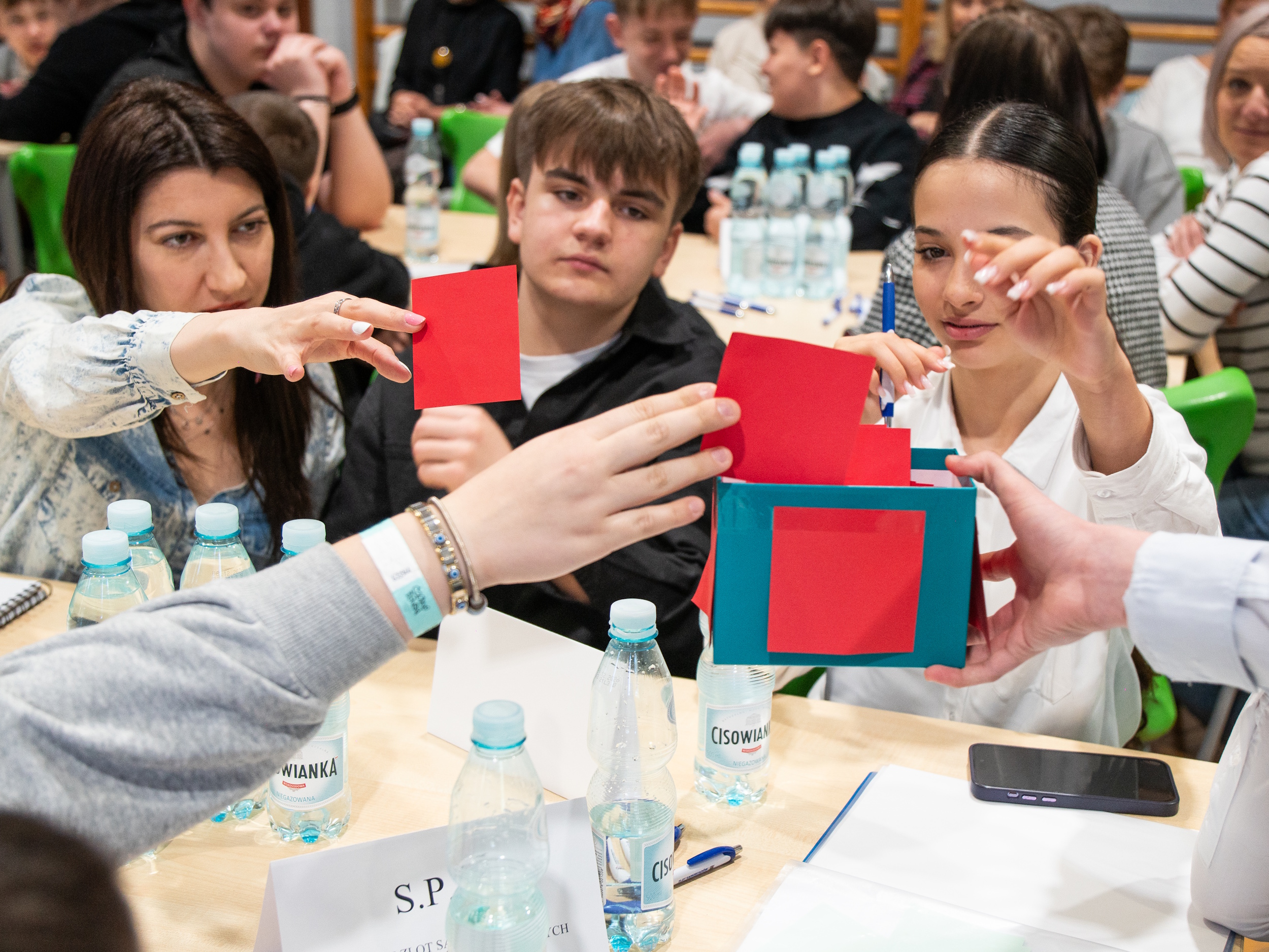 Uczniowie wrzucający karteczki do pudełka