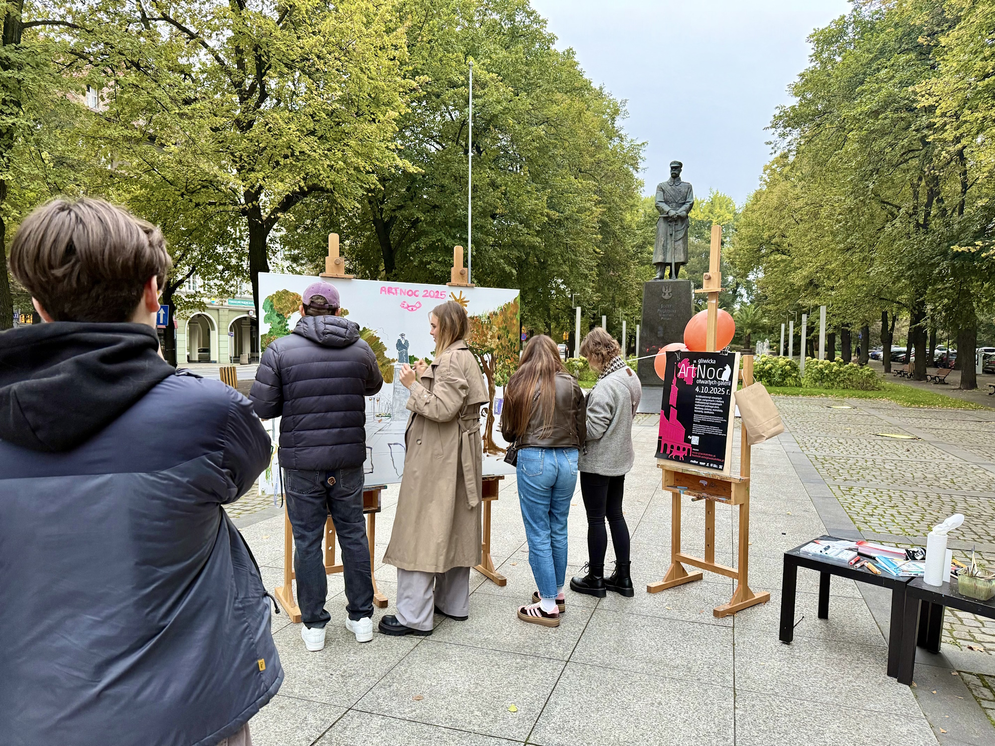 Ludzie przy sztalugach na placy Piłsudskiego