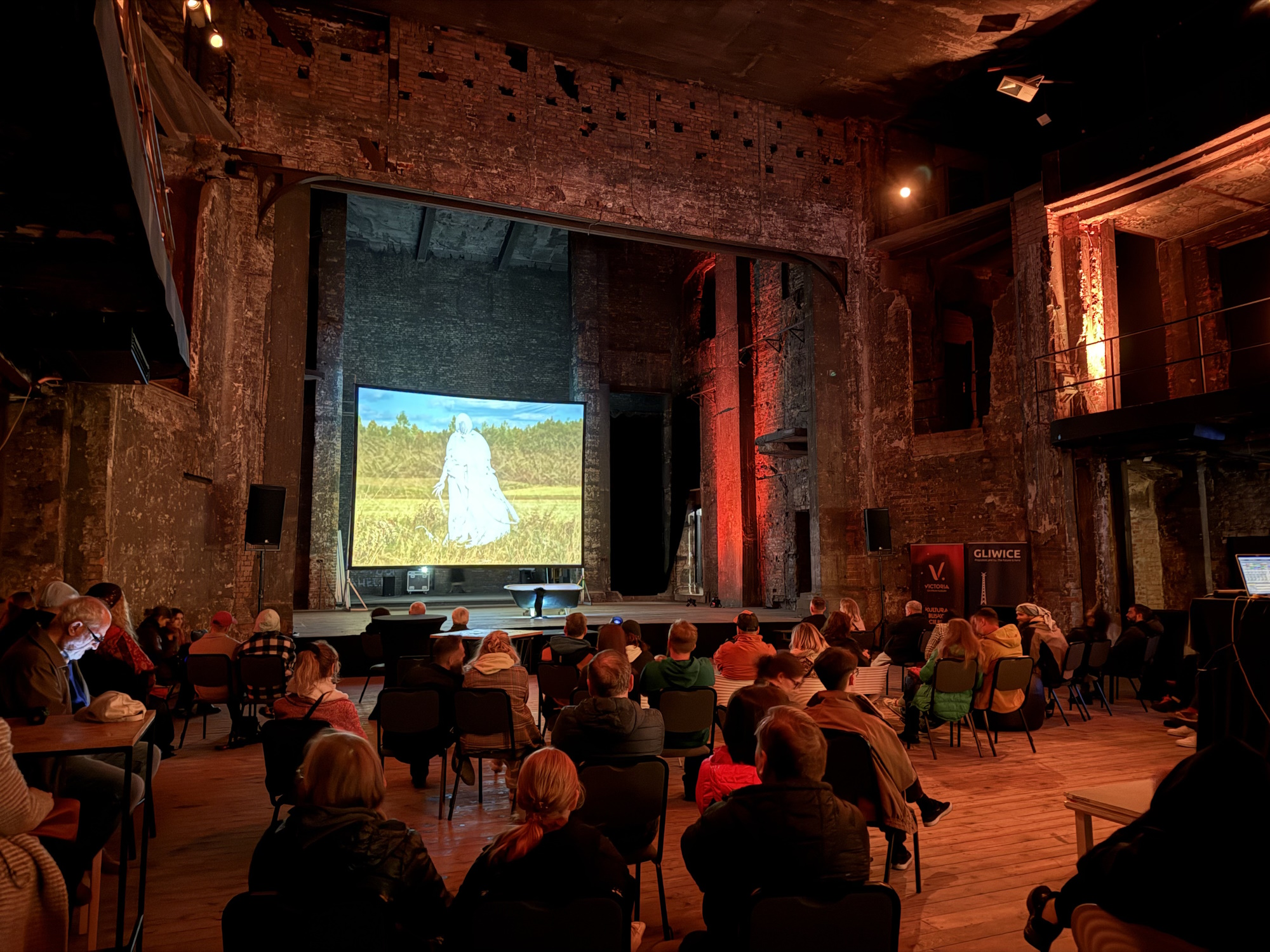 Ludzie siedzą na krzesłach i oglądają film w Ruinach Teatru Victoria