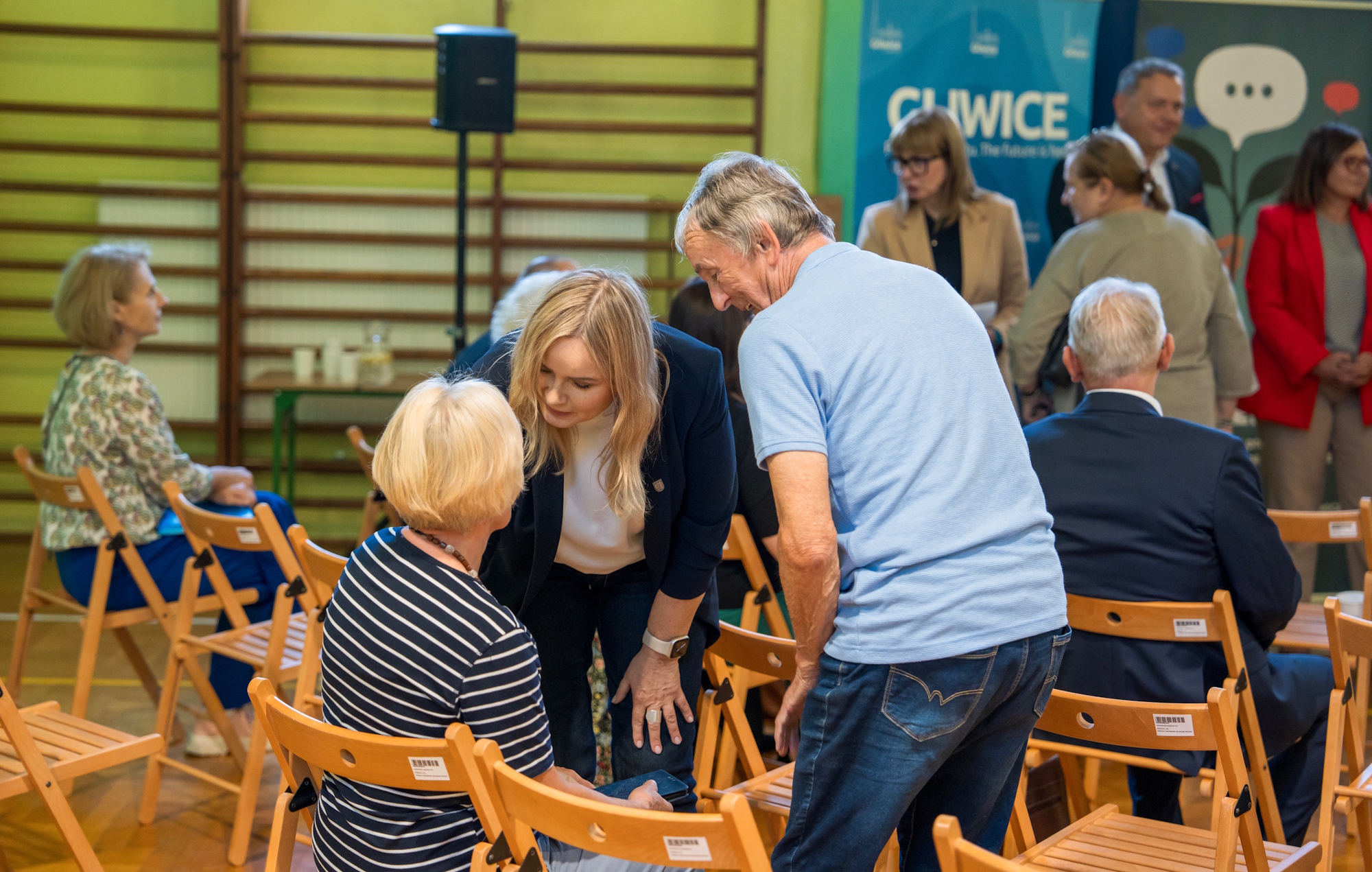 prezydent Gliwic rozmawia z siedzącą kobietą i stojącym obok mężczyzną