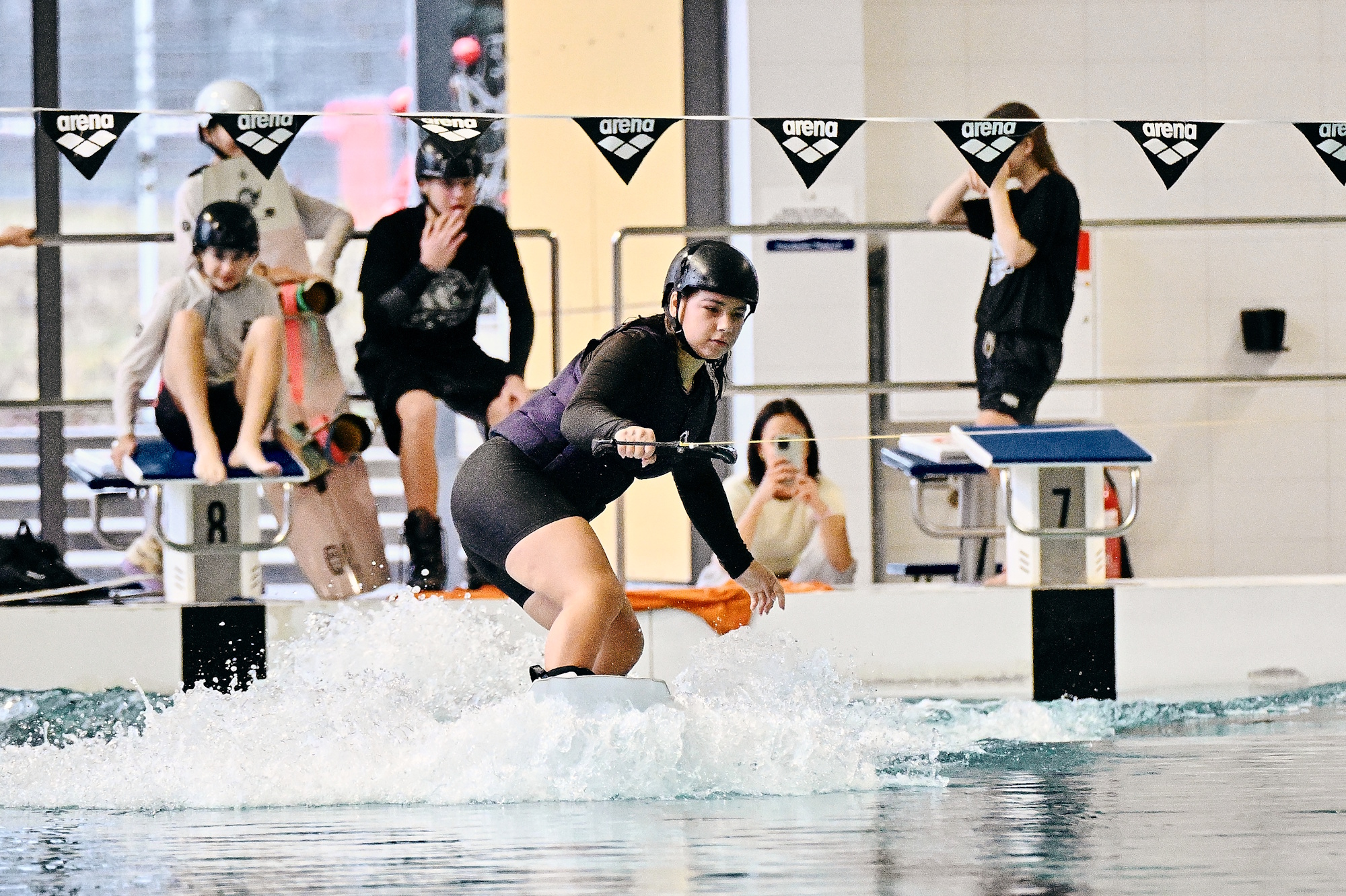 ludzie na basenie, jedna osoba w kasku na desce