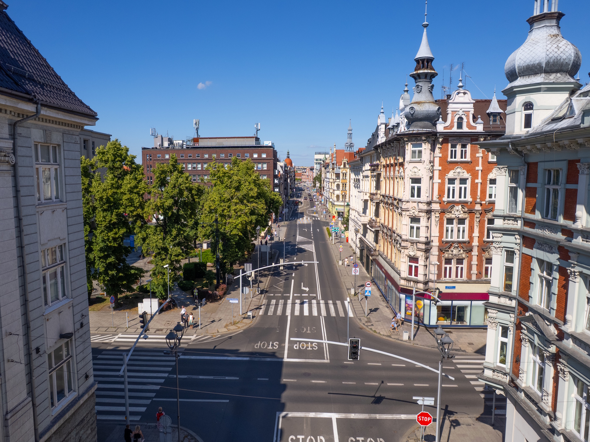 Ulica Zwycięstwa latem. Ujęcie z góry na kamienice, ulicę i samochody