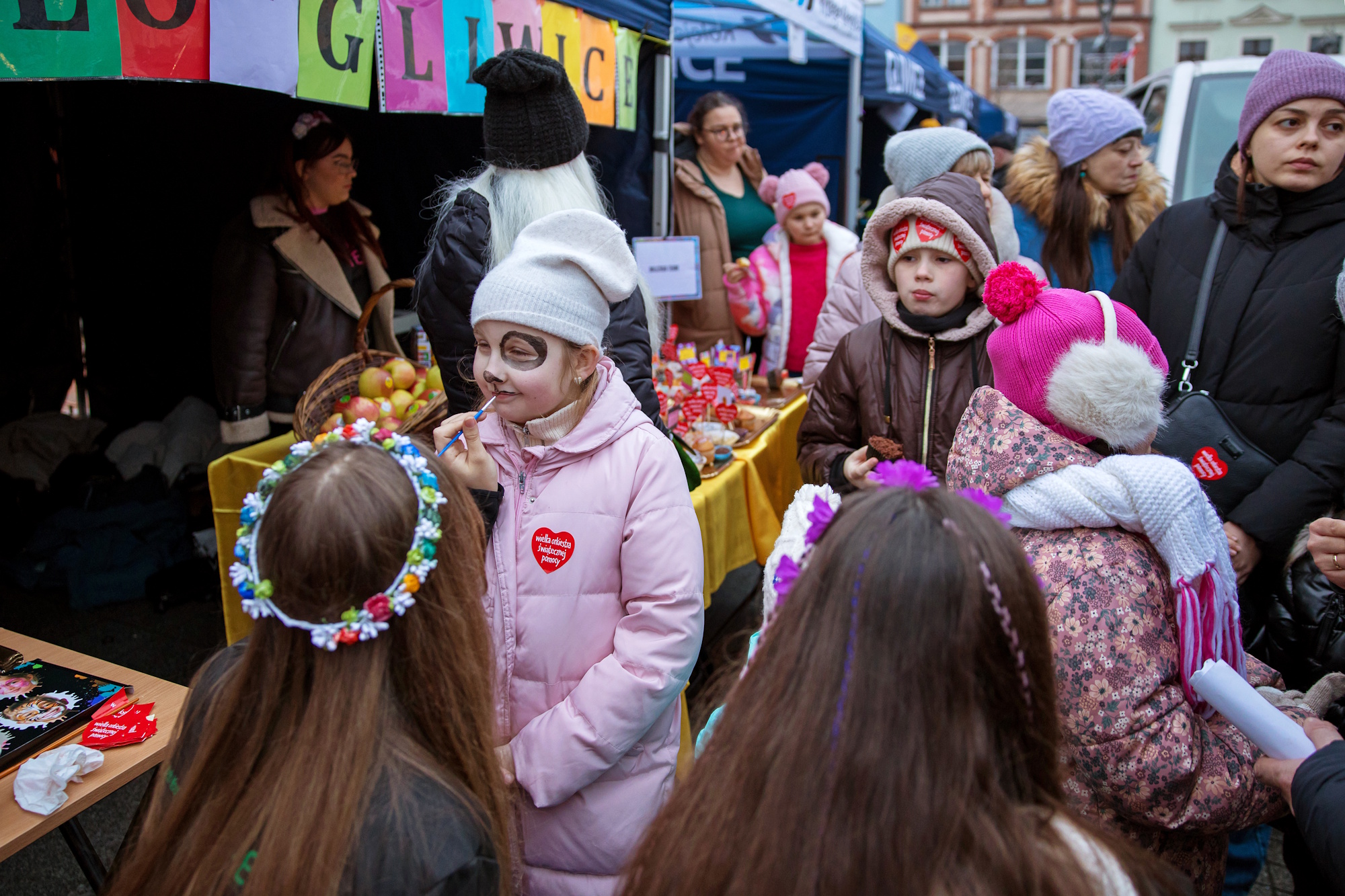 Ludzie na Rynku, animatorka przy stoisku maluje twarz dziewczynce