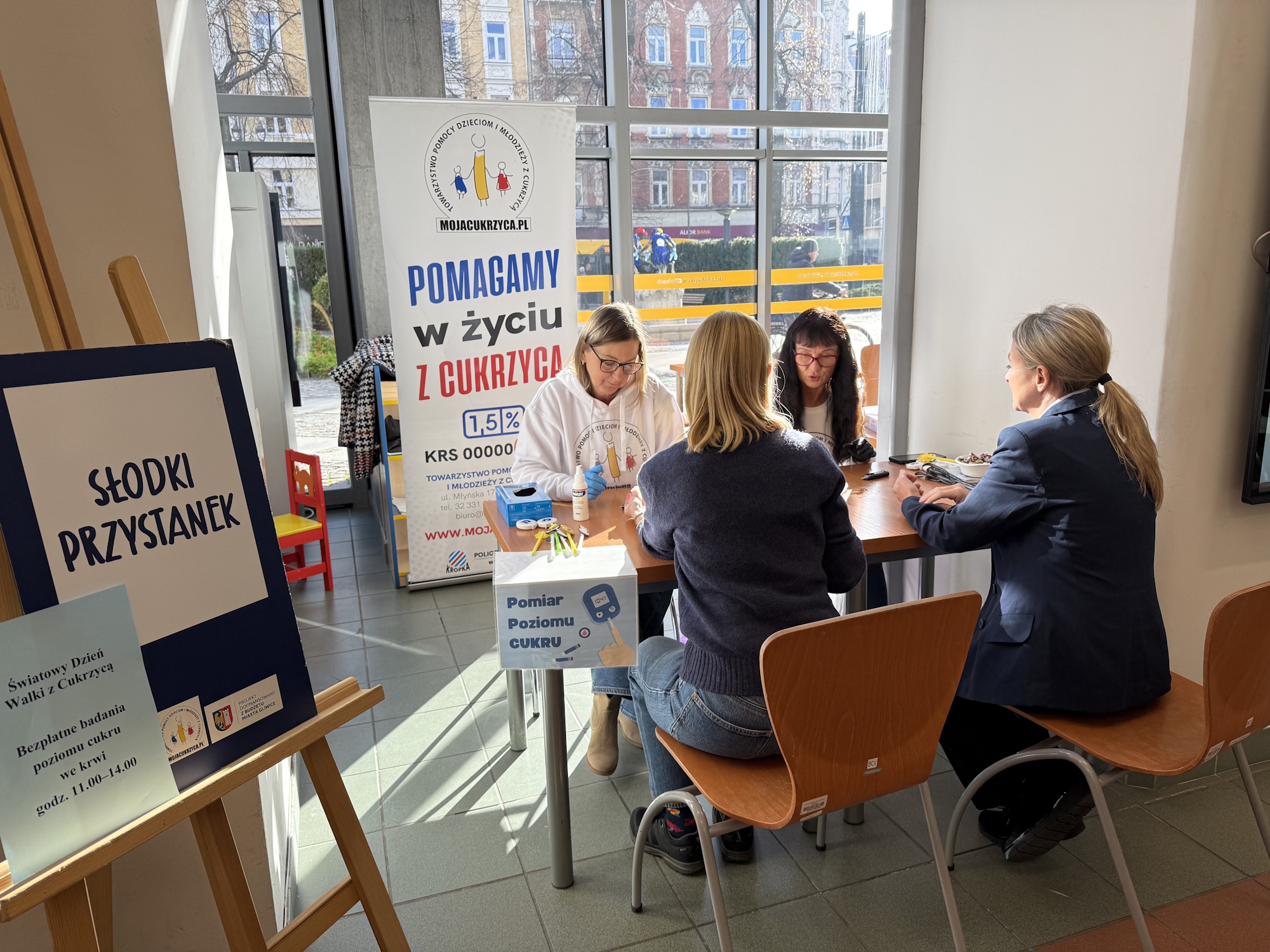 ludzie przy stoliku badają poziom cukru we krwi