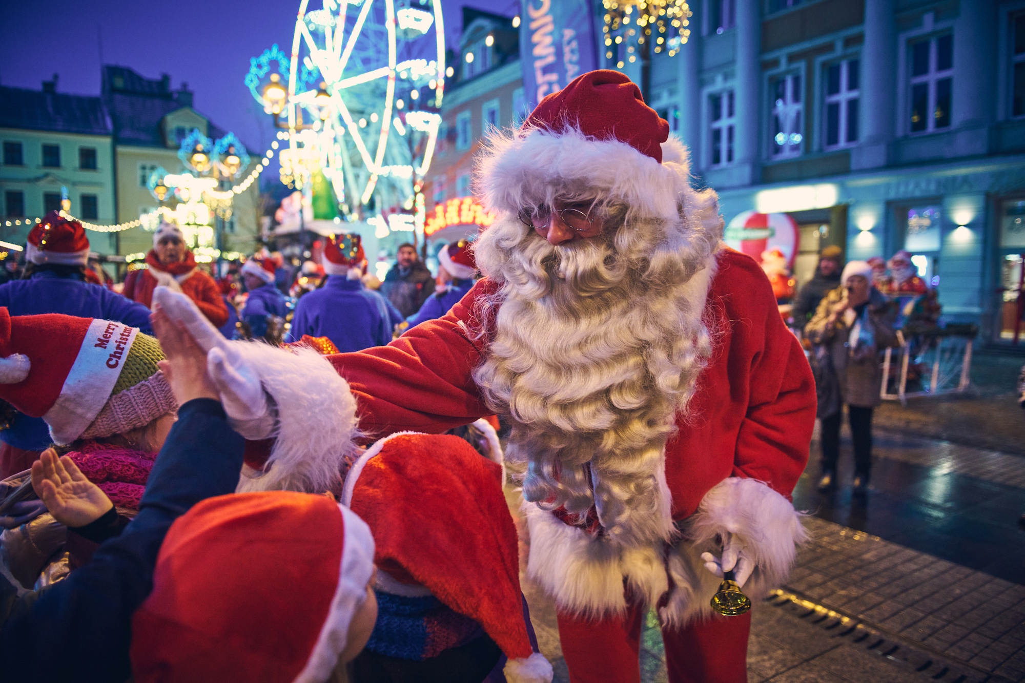 Mikołaj zbija piątkę z dzieckiem, w tle jarmark