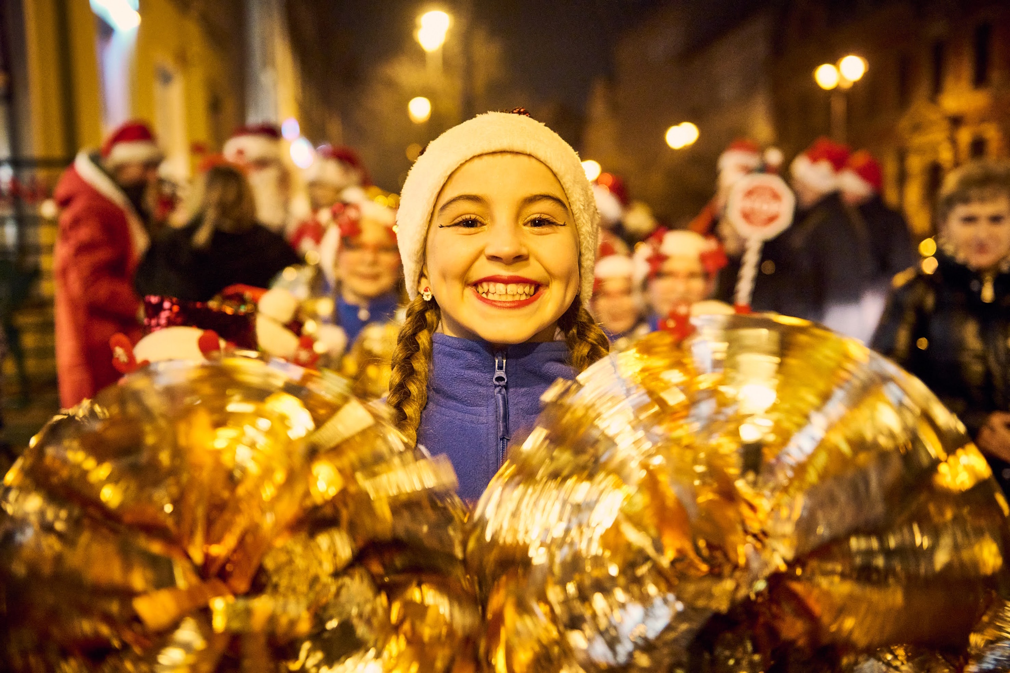 Uśmiechnięta dziewczynka z pomponami w rękach